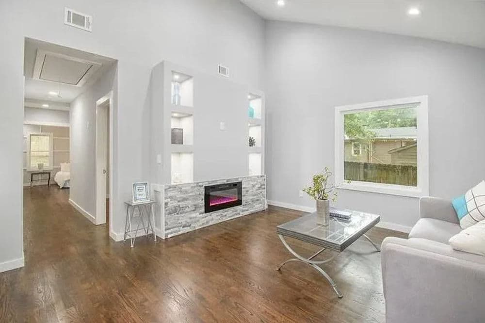 Modern living room with sleek furniture, decorative shelves, and a cozy electric fireplace.