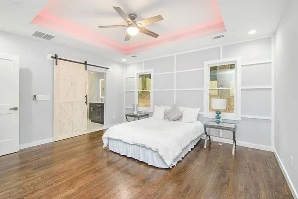 Modern bedroom with hardwood floors, ceiling fan, and stylish sliding barn door.